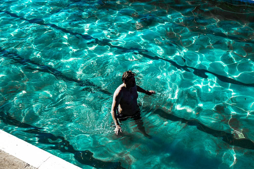 Adult beginner swimmer speaking with a swim coach at poolside
